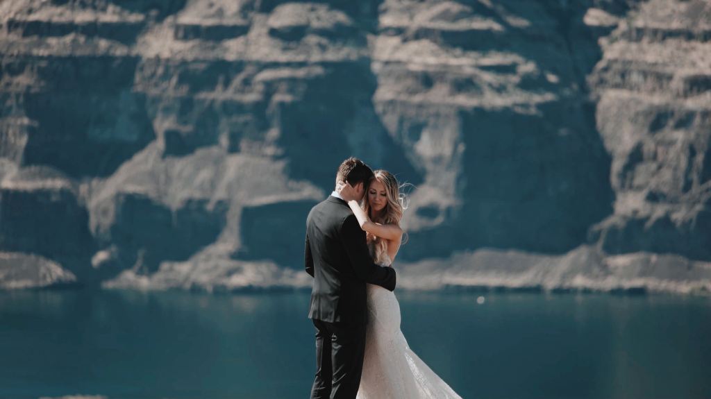 A bride and groom embracing with a massive cliff behind them