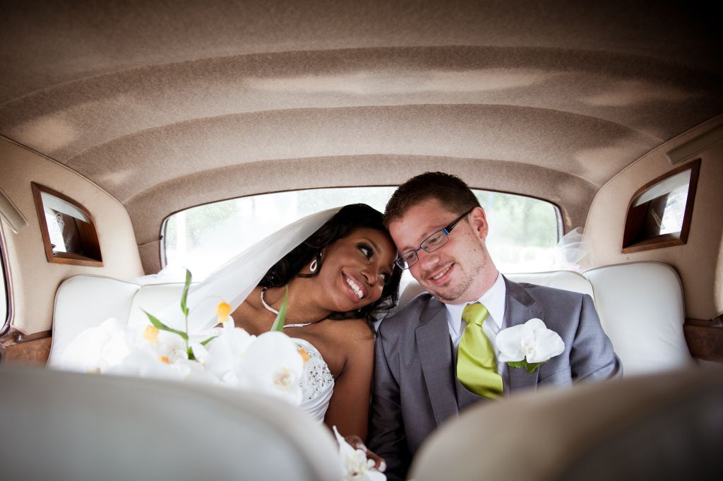 A bride and groom in an old fashioned car smiling