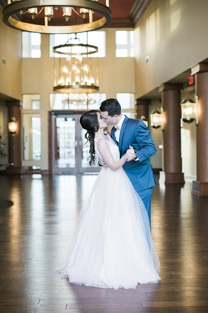 A bride and groom sharing a kiss inside of a tall hallway.