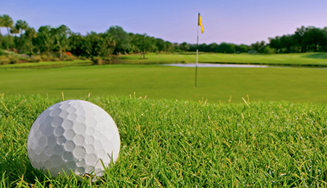 Close up of a golfball on the fairway with the green just ahead