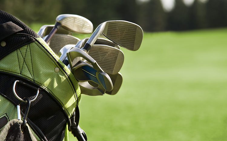 Close up of golf bag with golf clubs on a green background